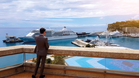 Ein Millionär blickt über Strand und Yachthafen